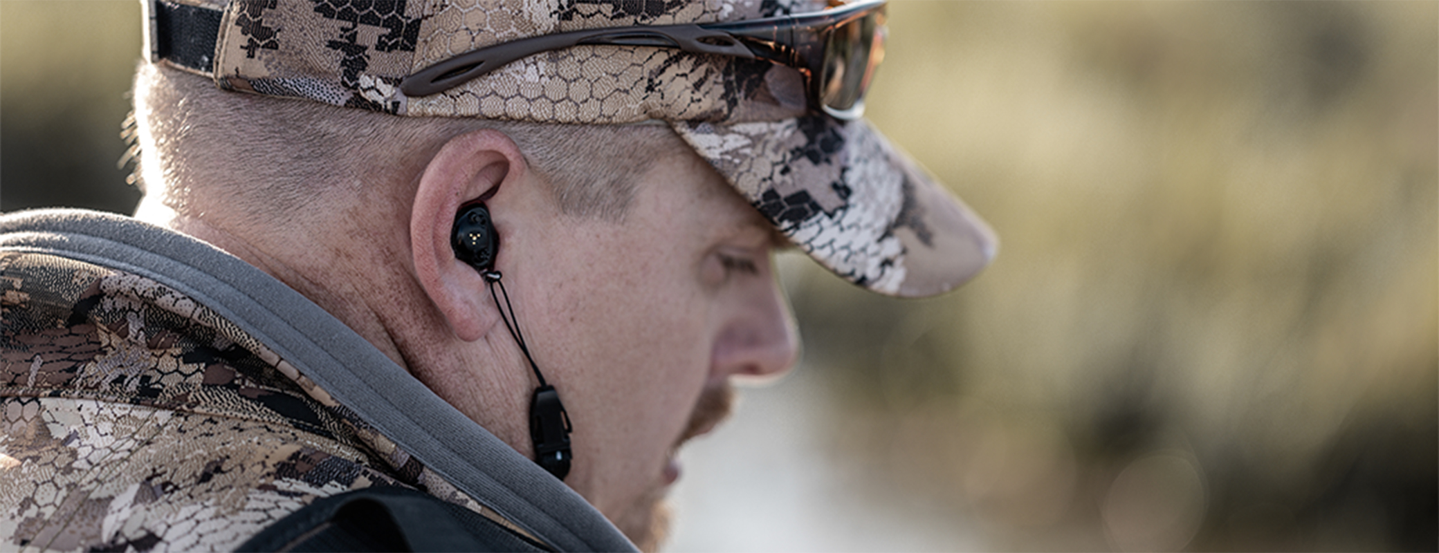 Close-up image of a hunter wearing hearing protection in his ears